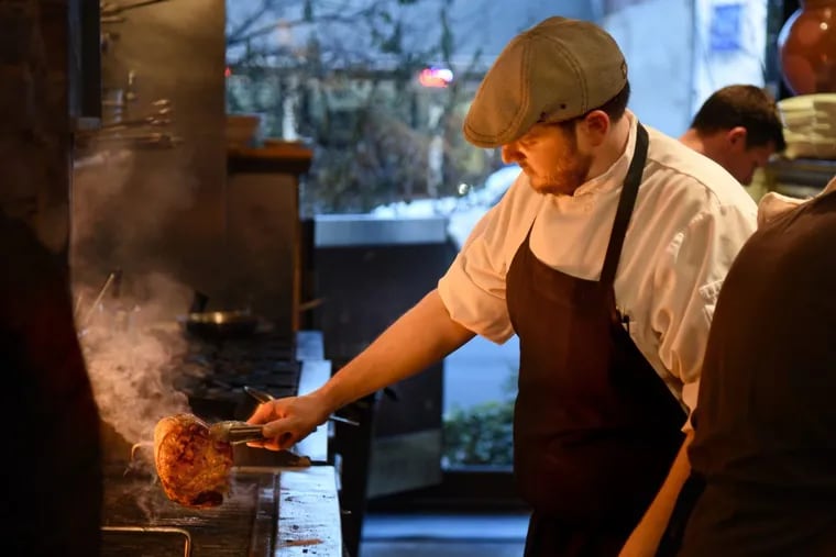 Chef de cuisine Jesse Grossman grills a pork chop in the kitchen at Osteria.