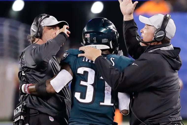 Defensive coordinator Jim Schwartz (right) and defensive backs coach Cory Undlin congratulate cornerback Jalen Mills after a fourth-down stop against the Giants last October.