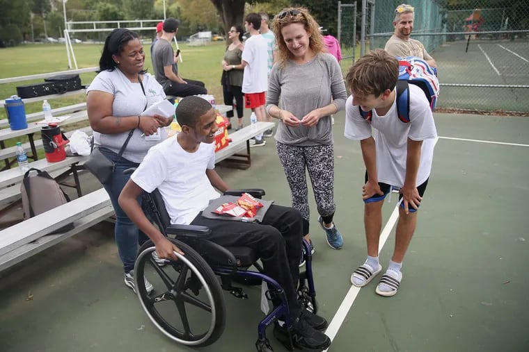 Zach Bookbinder talks with Azir Harris, who was paralyzed in a shooting last year. Bookbinder organized the fund-raising event with his mother, Hannah (beside Zach), after reading Harris’ story. At left is Harris' mother, Debra.