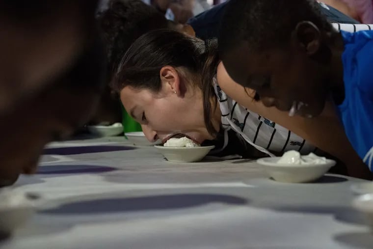 Nicole Ramirez, 15, dives head first into a bowl of vanilla ice cream in the Bassetts Ice Cream Eating Contest during last year's Philly Ice Cream Scoop at Reading Terminal Market. This year, the fest goes virtual.