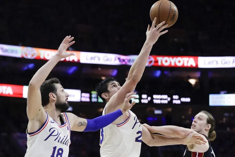 Sixers forward Ersan Ilyasova (center) reaches for the basketball with teammate Marco Belinelli over Miami forward Kelly Olynyk during the Sixers’ win on Saturday.