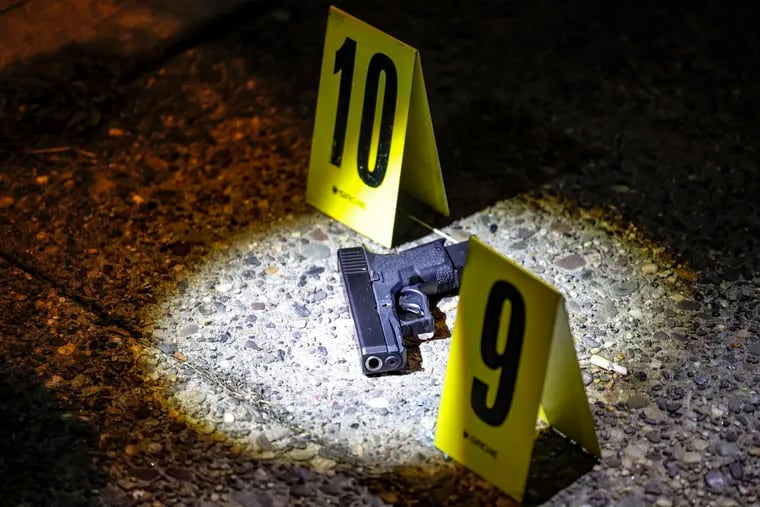 A handgun and crime-scene markers at the scene of a homicide near the intersection of 29th and Clearfield Streets in North Philadelphia, Thursday,  Dec. 7, 2023.