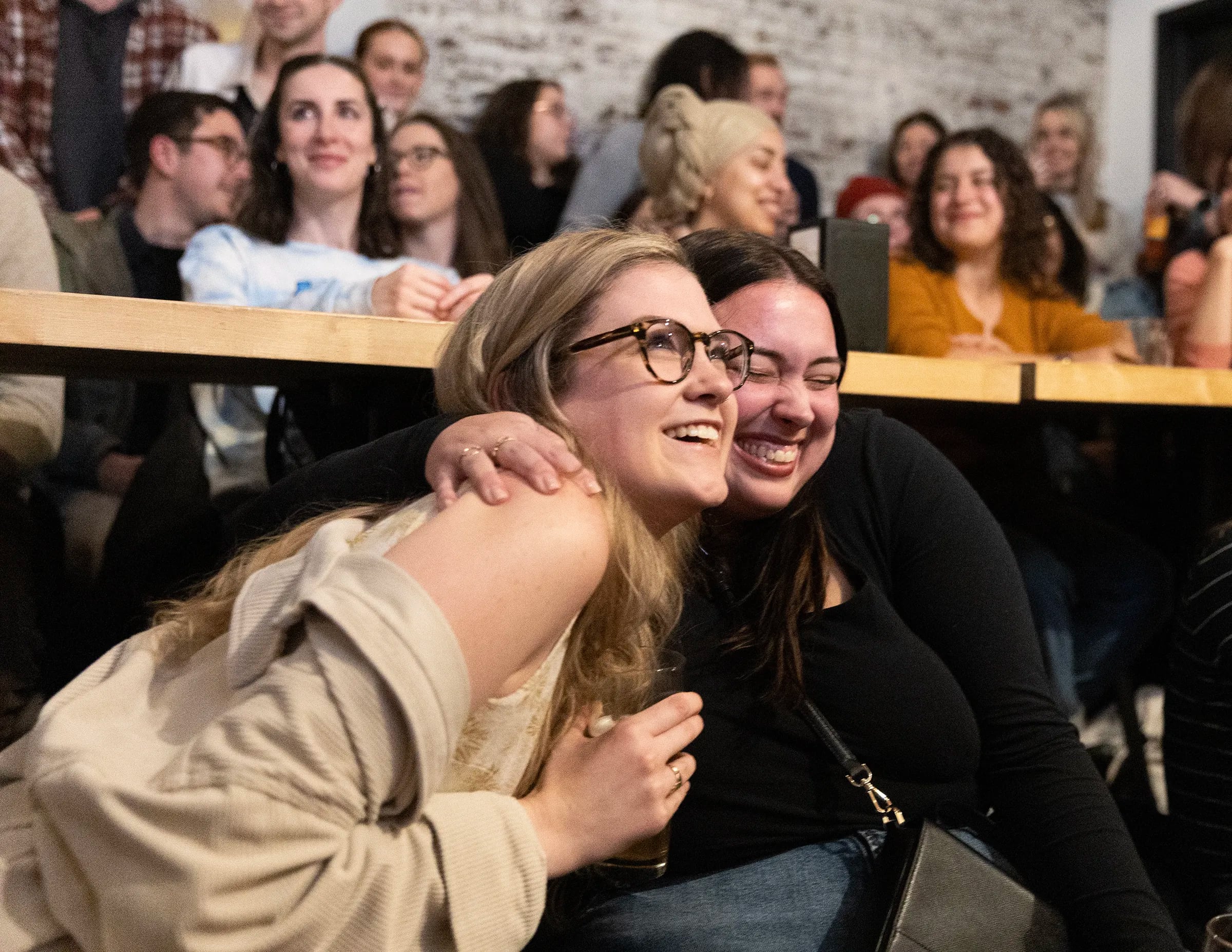 Kristen Coyne (left) gets a hug from Kayli McGlynn after Coyne made a presentation on her behalf at an event at Meyers Brewing.