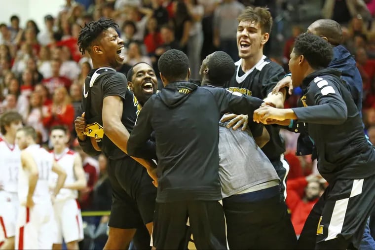 Lincoln players and coach Al Brown (foreground, second from left) celebrate after defeating Hazleton, 76-74, in overtime in a PIAA Class 6A basketball semifinal Saturday.