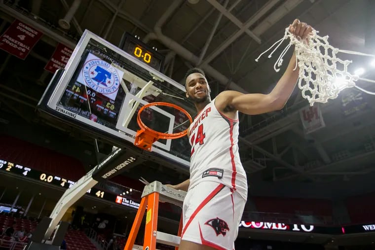 Donta Scott of Imhotep Charter holds up the net after making the final cuts. Imhotep defeated Constitution in the Boys Public League Championship at the Liacouras Center on Feb. 23, 2019. Scott was the Most Valuable Player.