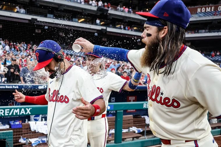 Phillies Whit Merrifield gets a water bath from teammates Bryson Stott behind and Brandon Marsh at right after sweeping the series with the Giants at Citizens Bank Park in Philadelphia, Monday, May 6, 2024 Phillies beat  the Giants 6-1.