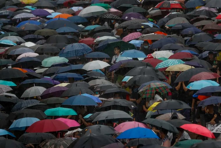 Protesters with umbrellas brave the rain during a rally in Hong Kong Sunday, Aug. 18, 2019. People are streaming into a park in central Hong Kong for what organizers hope will be a peaceful demonstration for democracy in the semi-autonomous Chinese territory. (AP Photo/Vincent Thian)