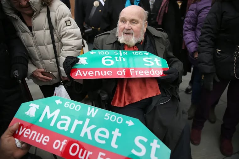 Tour guide Ed Mauger, who pushed for the new street sign names, looks over the Avenue of Freedom sign during a Monday ceremony at Sixth and Market Streets. Market Street was renamed Avenue of Our Founders.