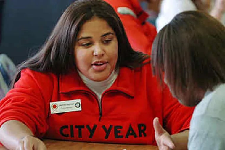 City Year volunteer Christina Graciano (left) offers some advice during a homework session with freshman Justina Hart at Overbrook High School. (Sarah J. Glover/Staff)
