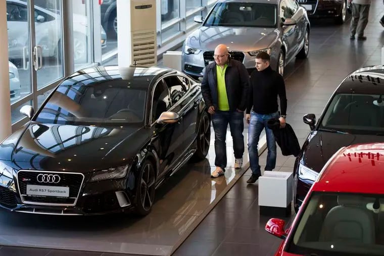 Customers walk among cars on display at a dealership in Moscow. Luxury cars are still in demand, with richer Russians scrimping elsewhere to afford them.