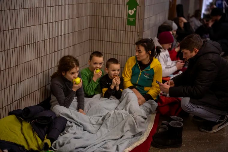 A family sit in the Kyiv subway, using it as a bomb shelter in Kyiv, Ukraine, Friday, Feb. 25, 2022. In Ukraine's capital, many residents hurried underground for safety overnight Thursday and Friday as Russian forces fired on the city and moved closer.