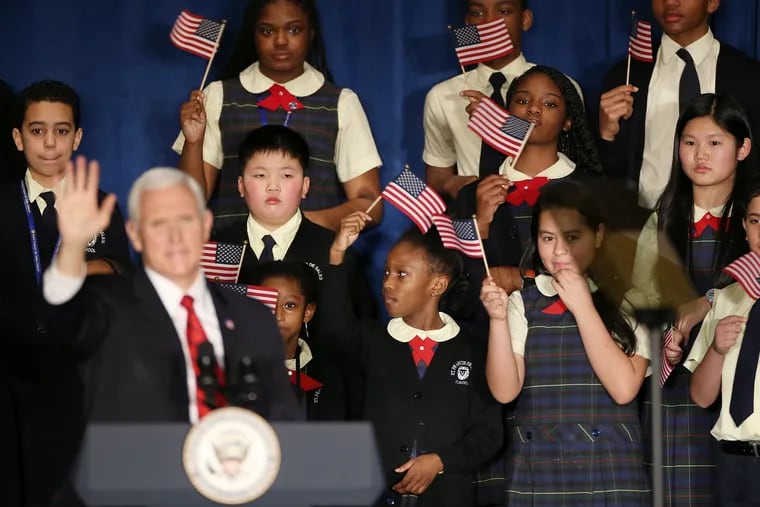 Students wave flags as Vice President Mike Pence speaks at St. Francis de Sales School in West Philadelphia on Wednesday. Pence and Secretary of Education Betsy DeVos were at the school for an event about school choice.