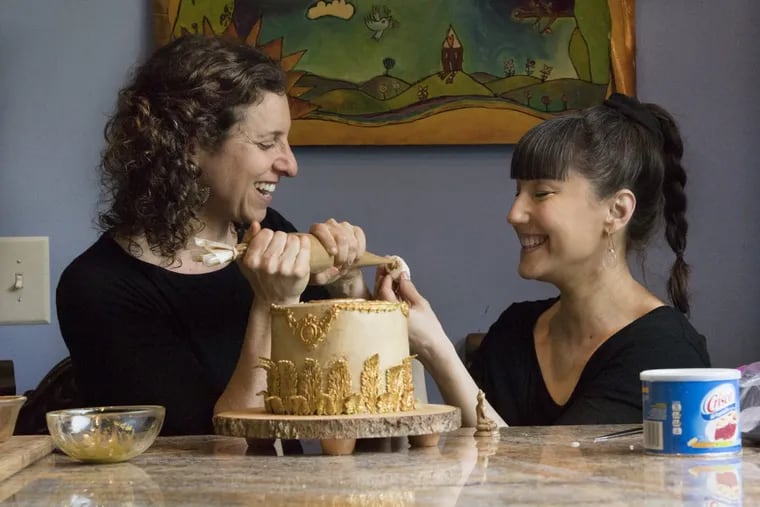 Tracy Phillips (left) and Sunshine O’Donnell decorate one of their CakeLabStudio creations at Phillips’ Philadelphia home.
