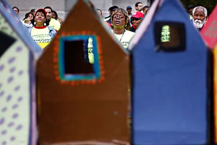 Small representations of houses frame people at a rally held by various low income housing advocacy groups at City Hall. They talked about a number of issues, including the city's 10 year tax abatement. (Eric Mencher/Inquirer)