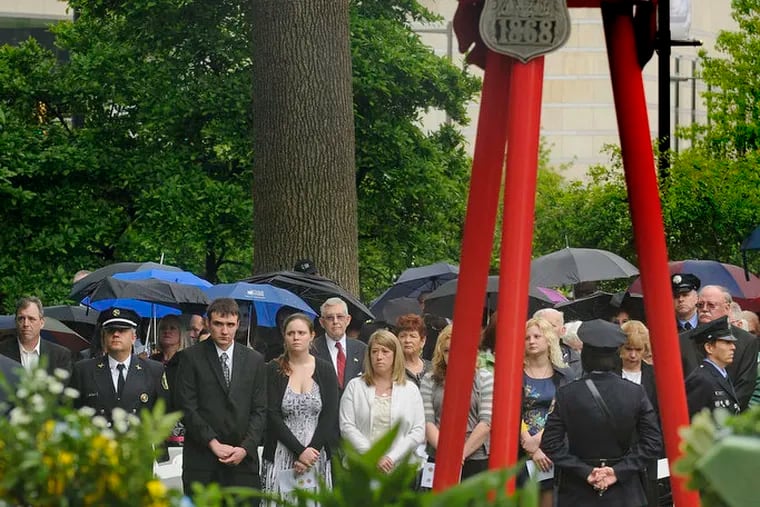 The family of Daniel Sweeney stands during Living Flame Memorial Service in Franklin Square May 2, 2012. Sweeney was one of two firefighters killed in the Kensington warehouse fire last month. ( TOM GRALISH / Staff Photographer )