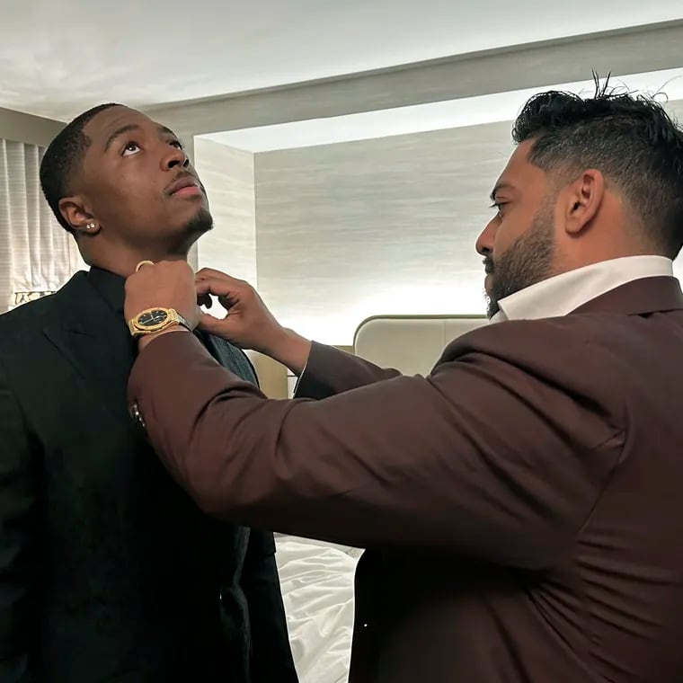 Ravi Punn, right, of Baynes + Baker, adjusts the collar on Eagles first-round pick Quinyon Mitchell during a final suit fitting for the draft on Thursday.