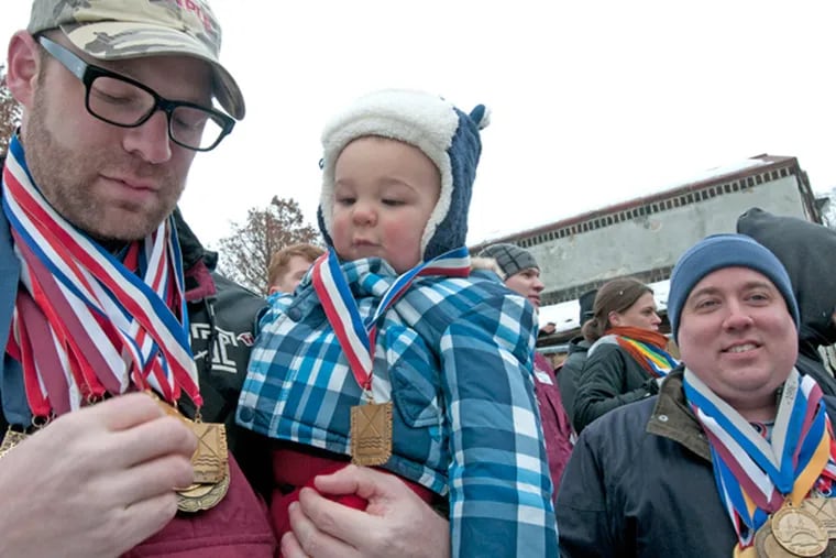 Dozens of past and present Temple rowers rallied Saturday at the Temple boathouse with their medals and trophies to protest the program being cut on Dec. 14, 2013. Here, Ferdinand Bergen and son, Christian, one year old, wear his medals; at right, Bernard Kiefer sports his. (APRIL SAUL/Staff)