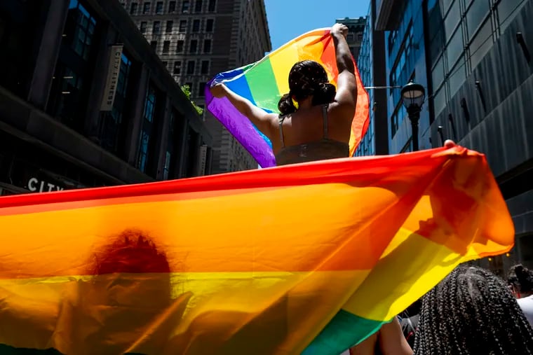 Marchers carry flags heading down 13th Street toward the Pride festival in the Gayborhood.