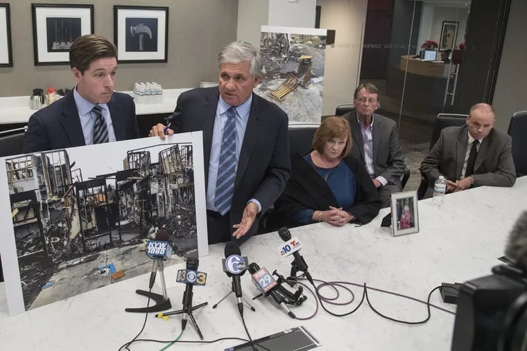 Attorney Robert Mongeluzzi (2nd left) and his partner Andrew Duffy (left), using a large photo, explain to the media during a press conference December 20, 2017 about where government officials believe last month’s nursing home fire at Barclay Friends Senior Living complex in West Chester started — on a covered outdoor patio. Seated at right are the children of Theresa Malloy, one of those killed in the fire, who are being represented by the lawyers. They are (from left) Mary Dimaio, Gary Malloy and Martin Malloy.