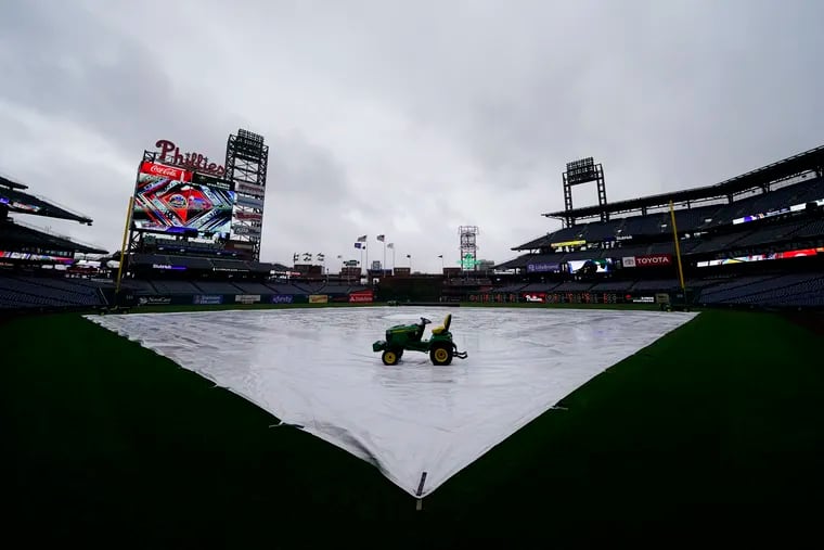 A tarp covers Citizens Bank Park under brooding skies on Saturday. The Phillies-Mets game was postponed and will be part of a single-admission doubleheader Sunday.