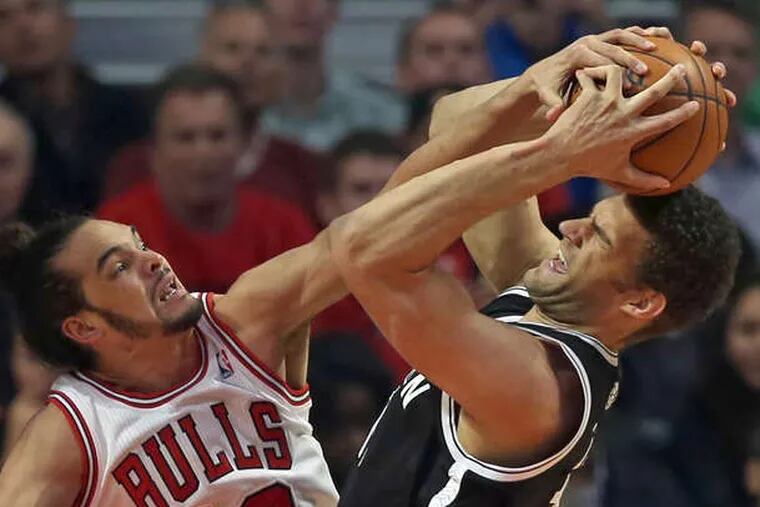 The Bulls' Joakim Noah blocks a shot by Brooklyn' Brook Lopez during first-quarter action. The Nets won Thursday's playoff game in Chicago, 95-92, forcing a Game 7. For NBA playoff coverage, go to Inquirer.com/sports.