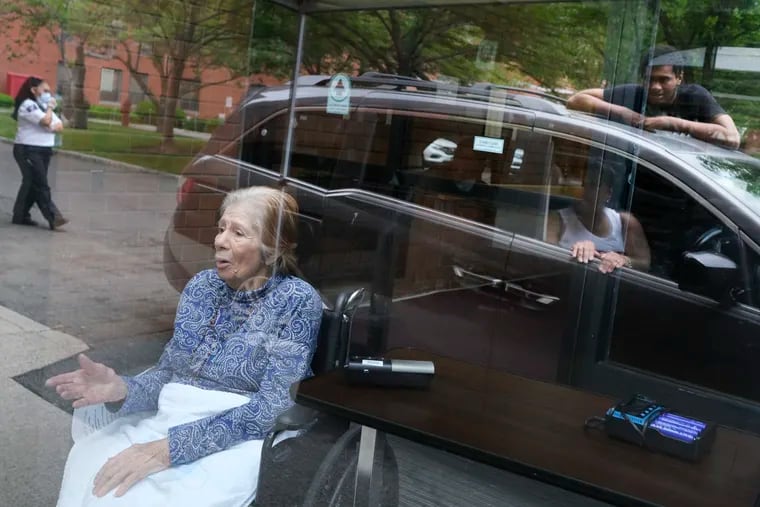 Gloria DeSoto, 92, bottom left, visits with her family, reflected in the glass in their car, from a window of the Hebrew Home at Riverdale, N.Y. on June 11.