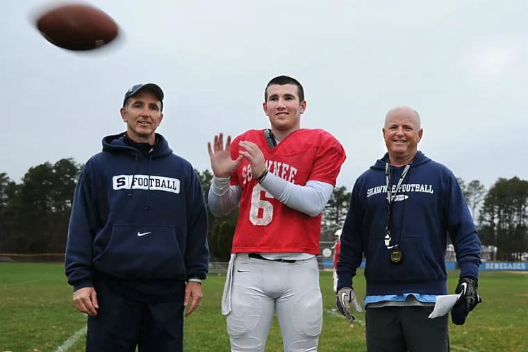 Shawnee quarterback Mike Welsh (center) poses with his dad, Shawnee assistant coach Tim Welsh (left) and Shawnee head coach Tim Gushue (right) at practice November 30, 2015.