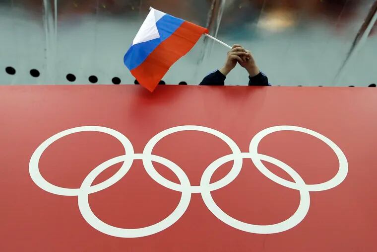 In this Feb. 18, 2014 file photo, a Russian skating fan holds the country's national flag over the Olympic rings before the men's 10,000-meter speedskating race at Adler Arena Skating Center during the Winter Olympics in Sochi, Russia. A person familiar with the case tells The Associated Press that Russia's anti-doping agency could face suspension again based on information indicating data from the Moscow drug-testing lab had been manipulated before being delivered to the World Anti-Doping Agency earlier this year.