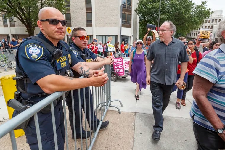 On Monday, June 24, 2019, Rabbi Shaun Zevit, right, directs his protest chants to the two Homeland Security Police officers, left, standing behind the barricade to the front door of the ICE headquarters on 8th Street, as protestors circle the block of the ICE Headquarters. Zevit is one of many Jewish Philadelphians who are drawing on Jewish ritual and text in their protests.