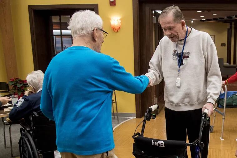 Retired Inquirer sports columnist Bill Lyon, right, greets Larry Singer at their assisted living  residence.