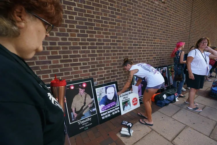 Denise Roccia adjusts a display of photographs of victims of the opioid crisis outside Federal Court while Safehouse, the group hoping to open a first-in-the-nation safe injection site in Philadelphia, goes to court to fight a Justice Department lawsuit asking for their proposal to be declared illegal, in Philadelphia, August 19, 2019.