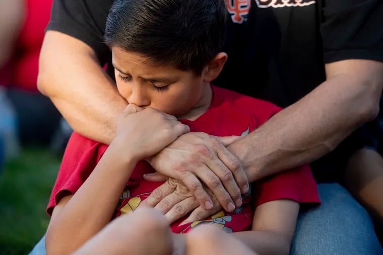 Robbie Ramirez, 10, holds onto his father, Robert Ramirez, during a vigil for victims of a Sunday evening shooting that left three people dead at the Gilroy Garlic Festival, Monday, July 29, 2019, in Gilroy, Calif.
