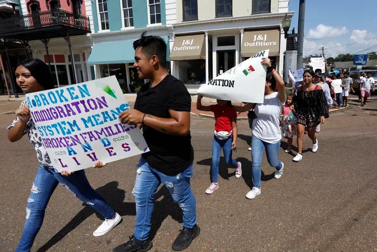 Children of mainly Latino immigrant parents hold signs in support of them and those individuals picked up during an immigration raid at a food processing plant in Canton, Miss.