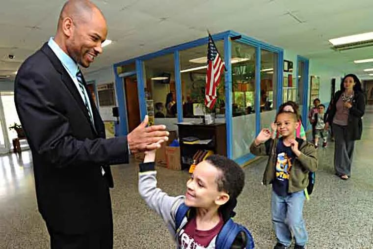 Dr. Kwame Norton, the principal at Kilmer Elementary in Cherry Hill, has been selected as the new principal at Cherry Hill High School West.  Here, Norton with kids at Kilmer on 5/15/13. In this photo, he's high-fiving Jayden Jefferson, 5; at right is Jordan Marrero, 6. ( APRIL SAUL / Staff )