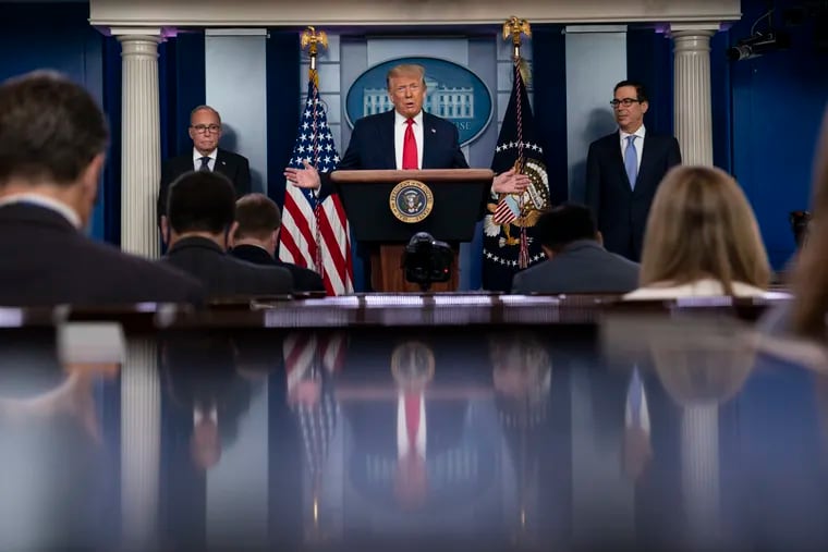 President Donald Trump speaks during a news briefing at the White House, Thursday, July 2, 2020, in Washington, as White House chief economic adviser Larry Kudlow, left, and Treasury Secretary Steven Mnuchin, look on.