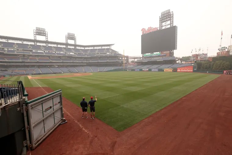 Phillies grounds crew employees watch the smokey haze from in front of the right field tunnel. The Detroit Tigers at Philadelphia Phillies MLB game at Citizens Bank Park on Wednesday was canceled because of the poor air quality caused by the smoke from the Canadian wildfires.
