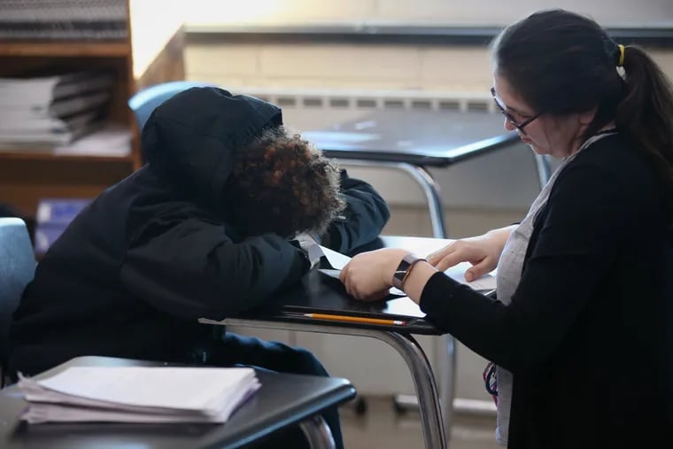 A teacher at Strawberry Mansion High School in Philadelphia encourages a sleeping student to work on his exam in 2019.
