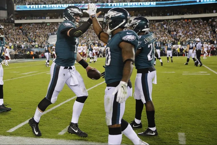 Eagles’ quarterback Carson Wentz, left, celebrates a second-quarter touchdown with Corey Clement (center) and Wendell Smallwood.