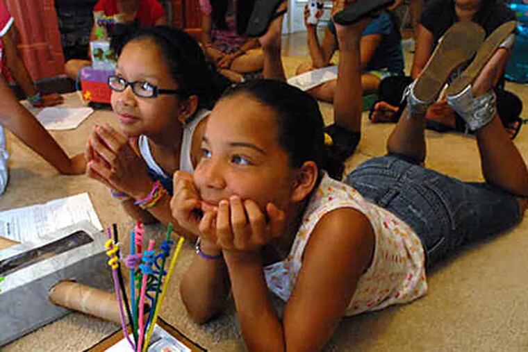 Girlblazers participants Kayleesha Rosario (left) and Ceannie Rosario watch fellow campers show inventions. Camp is held at the Mount Laurel institute named for suffragist Alice Paul. (April Saul / Staff)