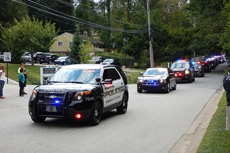 A procession of police, fire and ambulance vehicles escorted the body of Officer Robert "John" Miller past the Radnor Township Municipal Building as co-workers came out to pay their respects. (Mari A. Schaefer/Staff)