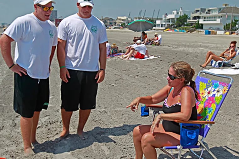 Beach badge bouncers Tim Goodwin (left) and Andrew Baumgardner talk with Linda O'Neill of Claymont, Del. The two men, both college football players, help Margate's beach-badge checkers enforce the town's tag law. (Akira Suwa/Staff)