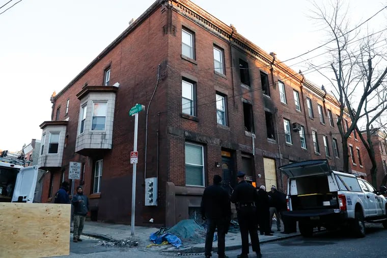 Members of the Philadelphia Police Department, Department of Housing Authority and Department of Licenses and Inspections stand outside the burned row home along the 800 block North 23rd Street in the Fairmount neighborhood on Monday, January 10, 2022.  Twelve people died, including nine children in the fire last week.