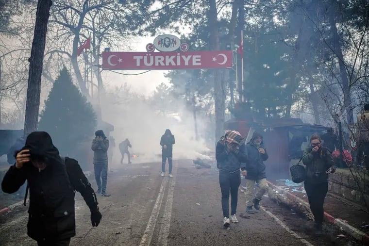 Greek border guards use teargas to push back migrants who try to enter Greece at the Pazarkule border gate, Edirne, Turkey, Saturday, Feb. 29, 2020.