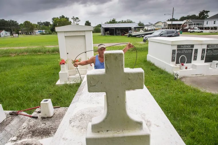 Jerry Parria uses steel cable and metal anchors to tie down four tombs belonging to his grandparents and uncles in a small cemetery near Lafitte, La.