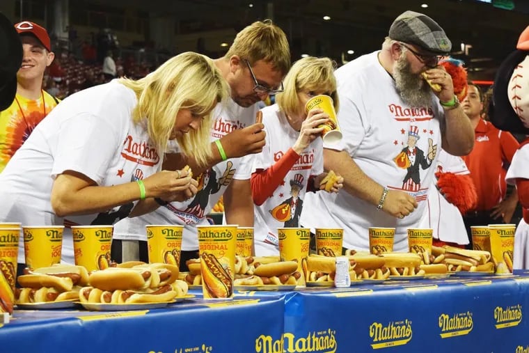 Rene Rovtar, pictured second from the right, downs some lemonade in between hot dogs at the Cincinnati, Ohio competitive eating qualifier for annual Nathan's Famous Fourth of July contest.