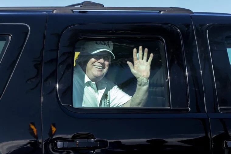 President Donald Trump waves to supporters from his motorcade traveling to Mar-a-Lago from Trump International Golf Club last Thursday.