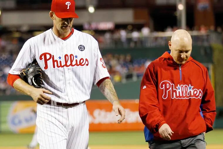 Phillies' pitcher A.J. Burnett walks to the Phillies dugout with head trainer Scott Sheridan during the fifth inning against the Miami Marlins.
