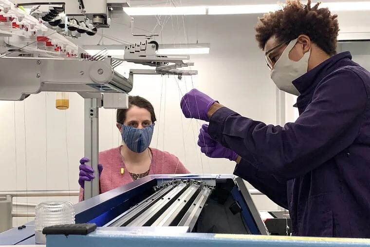 Chelsea Amanatides, left, and Keith Taylor, both textile fabrication technicians, on Tuesday, March 24, 2020, work at one of the Shima Seiki weft knitting machines used to make the masks they are wearing at the Pennsylvania Fabric Discovery Center at Drexel University.