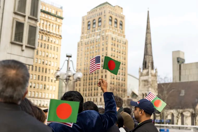 People in the Bangladeshi community hold up U.S. and Bangladeshi flags in front of the Municipal Services Building to celebrate the Golden Jubilee of Bangladesh and the Bangladesh Victory Day on Friday.