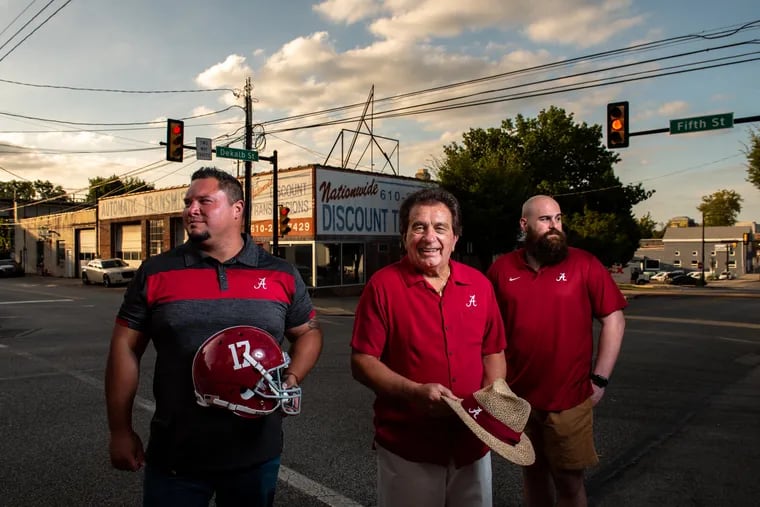 Joe Kekoanui, Johnny Nicola, and Terry Mulvey, members of the Bridgeport-based Alabama Booster Club, stand at the corner of Dekalb and Fifth Streets in the town. The club has provided scholarships for high school students across Pennsylvania to attend the University of Alabama since 1983,
